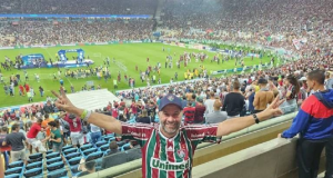 Lupi com camisa do Fluminense, sorrindo com braços abertos em estádio